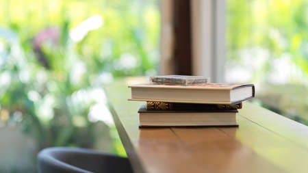 Cassette tape on books stacked on wooden bar in cafe with garden view in the backgroundの写真素材
