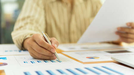 Cropped shot of businessperson working with business documents and laptop on wooden tableの写真素材