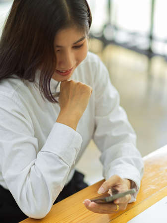 Cropped shot of female office worker relaxing with smartphone in office roomの写真素材