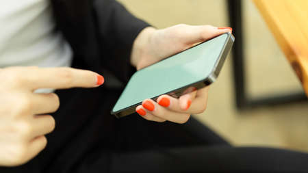 Side view of female office worker hands using smartphone with mock-up screen