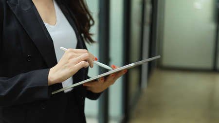 Side view of businesswoman working with digital tablet while standing in office workplaceの写真素材