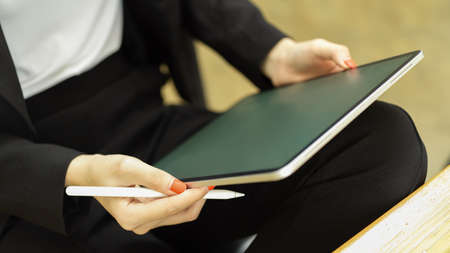 Close up view of businesswoman using with digital tablet while sitting in workplaceの写真素材