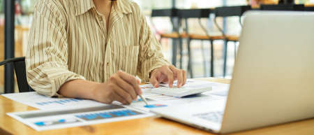 Cropped shot of businessperson working with business documents and laptop on wooden tableの写真素材