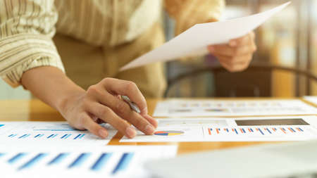 Close up view of businessperson hand working with paperwork and laptop on office deskの写真素材
