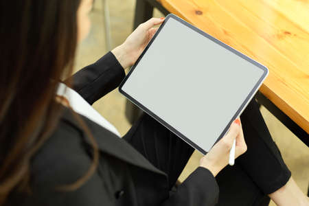 Top view of businesswoman using digital tablet with mock-up screen while relaxed sitting at workplaceの写真素材