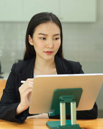 Portrait of businesswoman concentrating on her work with digital tablet in office roomの写真素材