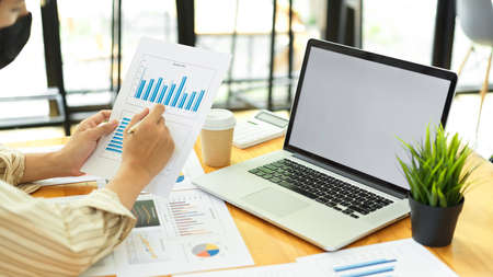 Side view of businessman hands working with paperwork and laptop in comfortable office roomの写真素材