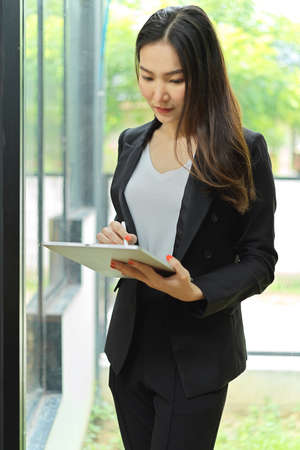 Portrait of businesswoman using digital tablet while relaxing in office buildingの写真素材