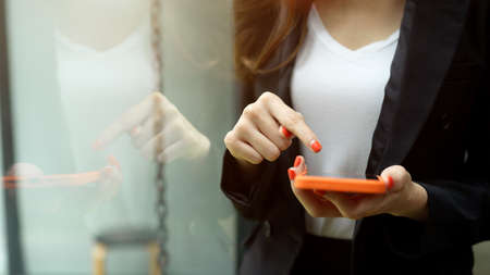 Close up view of businesswoman using smartphone while relaxing in office buildingの写真素材