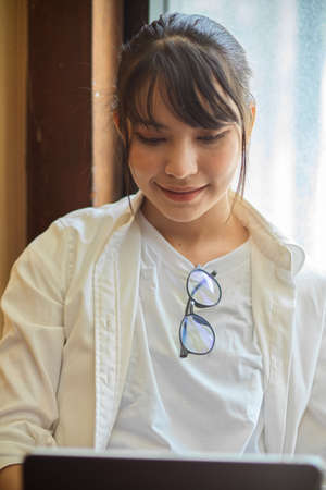 Half-length portrait of young female smiling and  teenager using computer device in cafeの写真素材