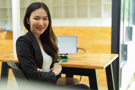 Portrait of businesswoman smiling to camera while sitting at relaxing corner in office buildingの写真素材