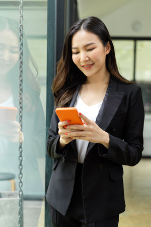 Portrait of businesswoman using smartphone while relaxing in office buildingの写真素材