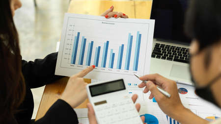 Close up view of businesspeople consulting on their project with paperwork and calculatorの写真素材