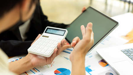 Side view of businesspeople consulting on their project with paperwork and calculator in office roomの写真素材