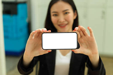 Businesswoman hands holding smartphones with horizontal mock-up screen and showing to cameraの写真素材