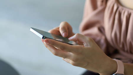 Close up view of female office hands texting message on smartphone while relaxing in office roomの写真素材