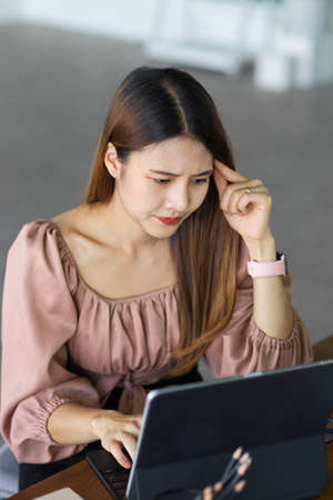 Portrait of young female worker concentrating on her work with digital tablet in cafeの写真素材