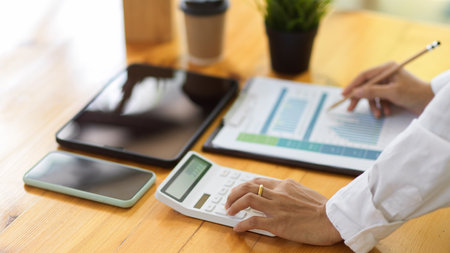 Side view of businessperson hands working with calculator and business paperwork on office deskの写真素材