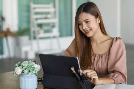 Happy young female office worker working on digital tablet in office roomの写真素材