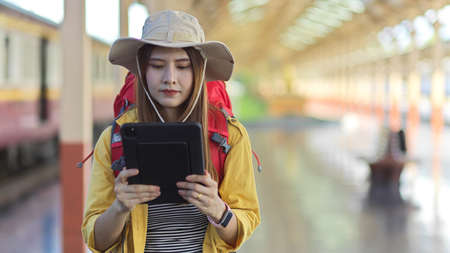 Portrait of female traveller holding digital tablet while working in platform at train stationの写真素材