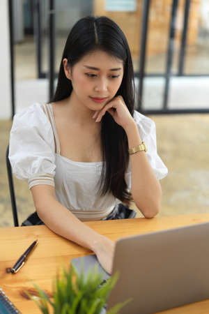 Portrait of young female teenager concentrating on her assignment with laptopの写真素材