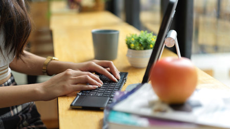 Side view of female hands typing on wireless keyboard with working with digital tablet in cafeの写真素材