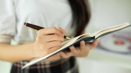 Close up view of female office worker checking her schedule while working in office roomの写真素材