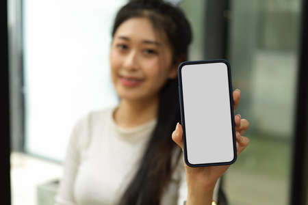 Close up view of female holding smartphone and showing mock-up screen to cameraの写真素材