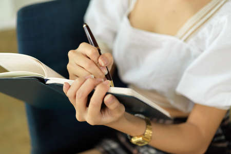 Top view of female handwriting on schedule book while working in meeting roomの写真素材