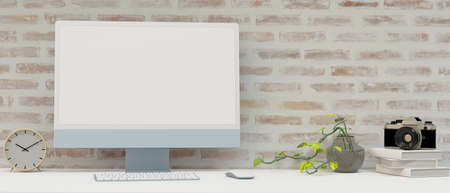 Computer monitor with mock-up screen on the desk with books, camera and decorationの写真素材