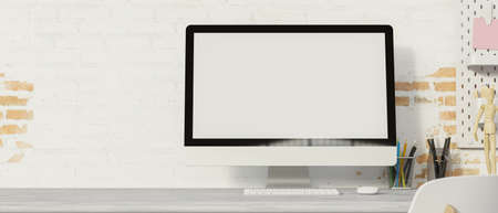 Computer monitor with mock-up screen on the desk with supplies and brick wall background, 3D rendering, 3D illustrationの写真素材