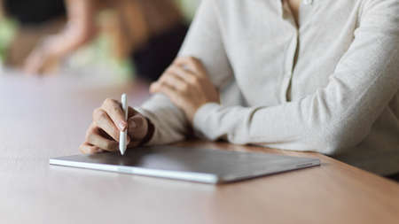 Close-up view of female using tablet with stylus pen to take notes while meeting, Female using tablet with stylus pen conceptの写真素材