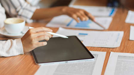 Close up business team using tablet with stylus pen and looking on the financial documents at the meeting roomの写真素材