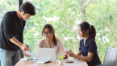 Portrait of 3 workers meeting and discussing in the meeting room with laptop, financial papers and office suppliesの写真素材