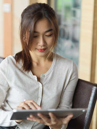 Portrait of asian businesswoman focusing and working on tablet while holding stylus penの写真素材