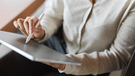 Businesswoman working on tablet while holding stylus penの写真素材