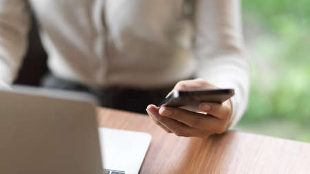 Cropped shot businessman working on laptop and holding mobile phone on the deskの写真素材