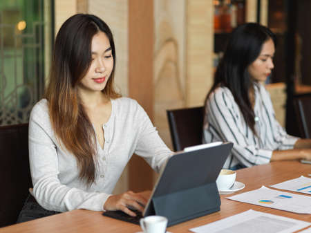Workingwoman working on laptop in the office room with colleague and the documents on the deskの写真素材