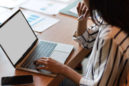 Cropped portrait of business female browsing on generic laptop with blank desktop screen at officeの写真素材