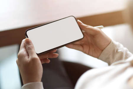 Close up of blank horizontal smartphone screen, female holding smartphone with blank copy spaceの写真素材