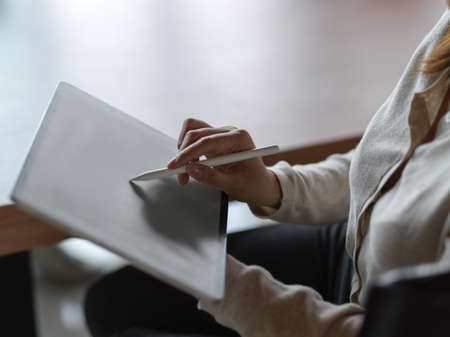 Close up of businesswoman hand working on digital tablet with stylus pen and blurred background