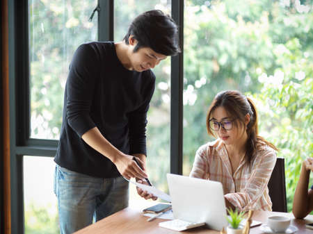 Businessman and businesswoman consulting their project together at office with blurry backgroundの写真素材