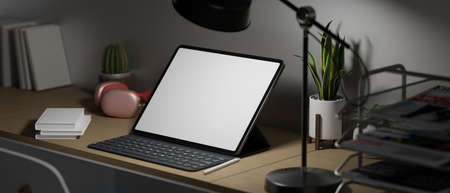 Late night overwork, Side view of empty screen tablet with keyboard, pink headphone, books, plant and decor in low light home office, 3d rendering, 3d illustrationの写真素材