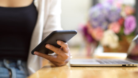 Cropped shot of female texting on smartphone, college browsing information via mobile phone, freelancer message to clients via online applicationの写真素材