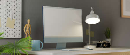 Home office space in stylish design, with blank screen computer, figure, camera, table lamp and decor stuff on desk and grey wallpaper, 3d rendering, 3d illustrationの写真素材