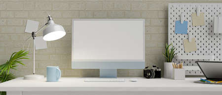 Modern apartment work space with desktop computer in empty screen, camera, table lamp, shelf and stuff in front of modern brick wall, 3d rendering, 3d illustrationの写真素材
