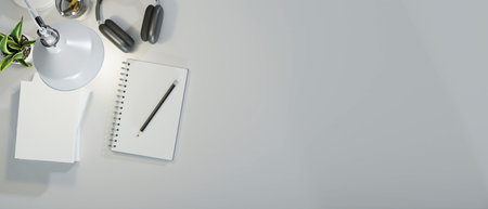 Minimal work space in white decor with book, pencils, headphone, tree pot and light from table lamp, creative desk with copy space for your brands, top view, 3d rendering, 3d illustrationの写真素材