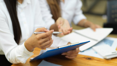 Cropped shot of two young female worker discussing their work project with financial reportの写真素材