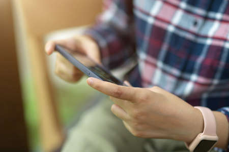 Close up young male using smartphone, watching video, playing gameの写真素材