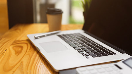 Close up of computer laptop with stuff and decor on wooden tableの写真素材